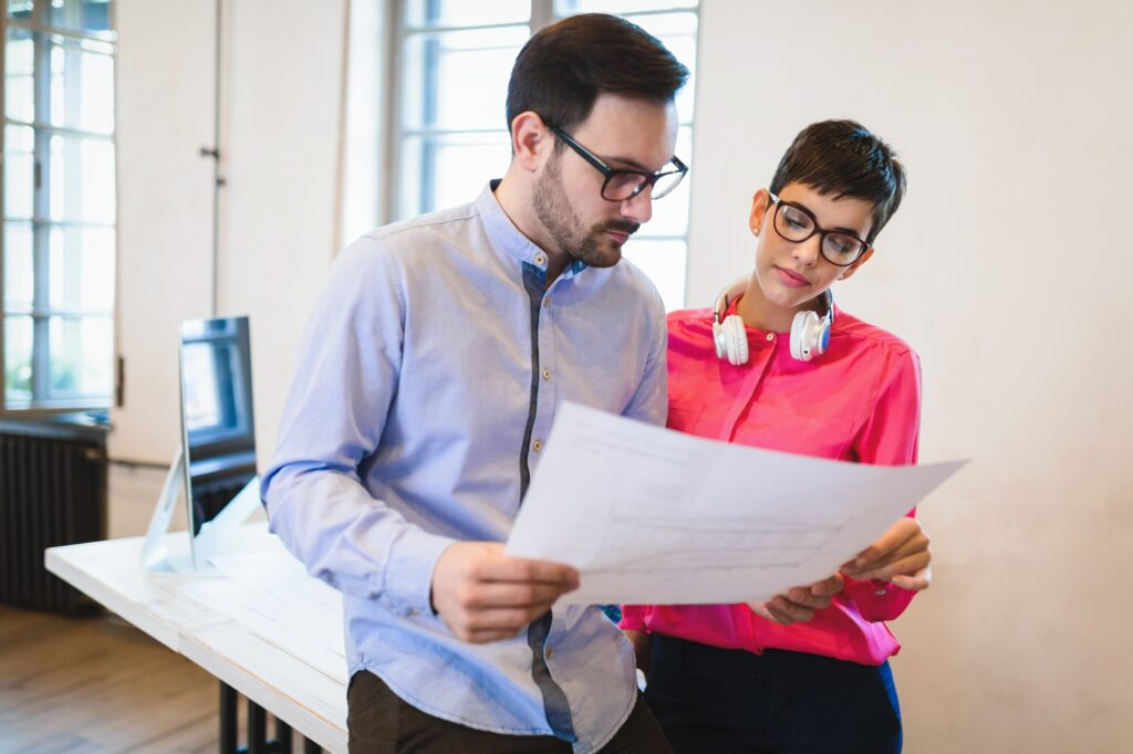 Group of young perspective architects looking at project papers
